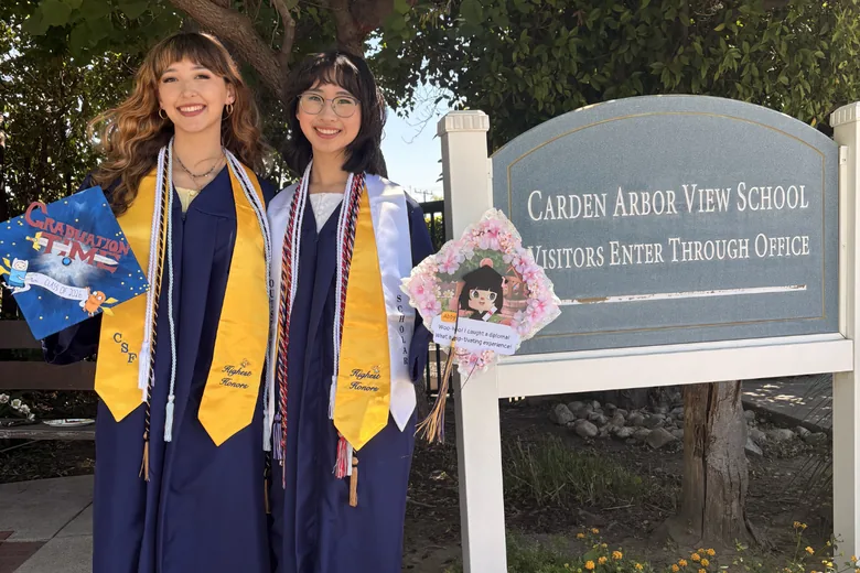 Graduates visiting the Carden Arbor View campus sign