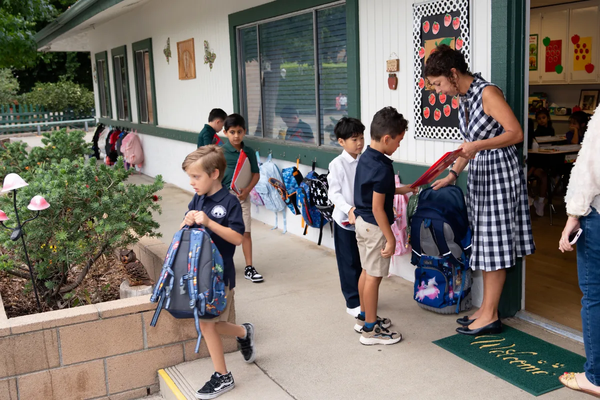 A Carden Arbor View teacher welcoming students at the classroom door